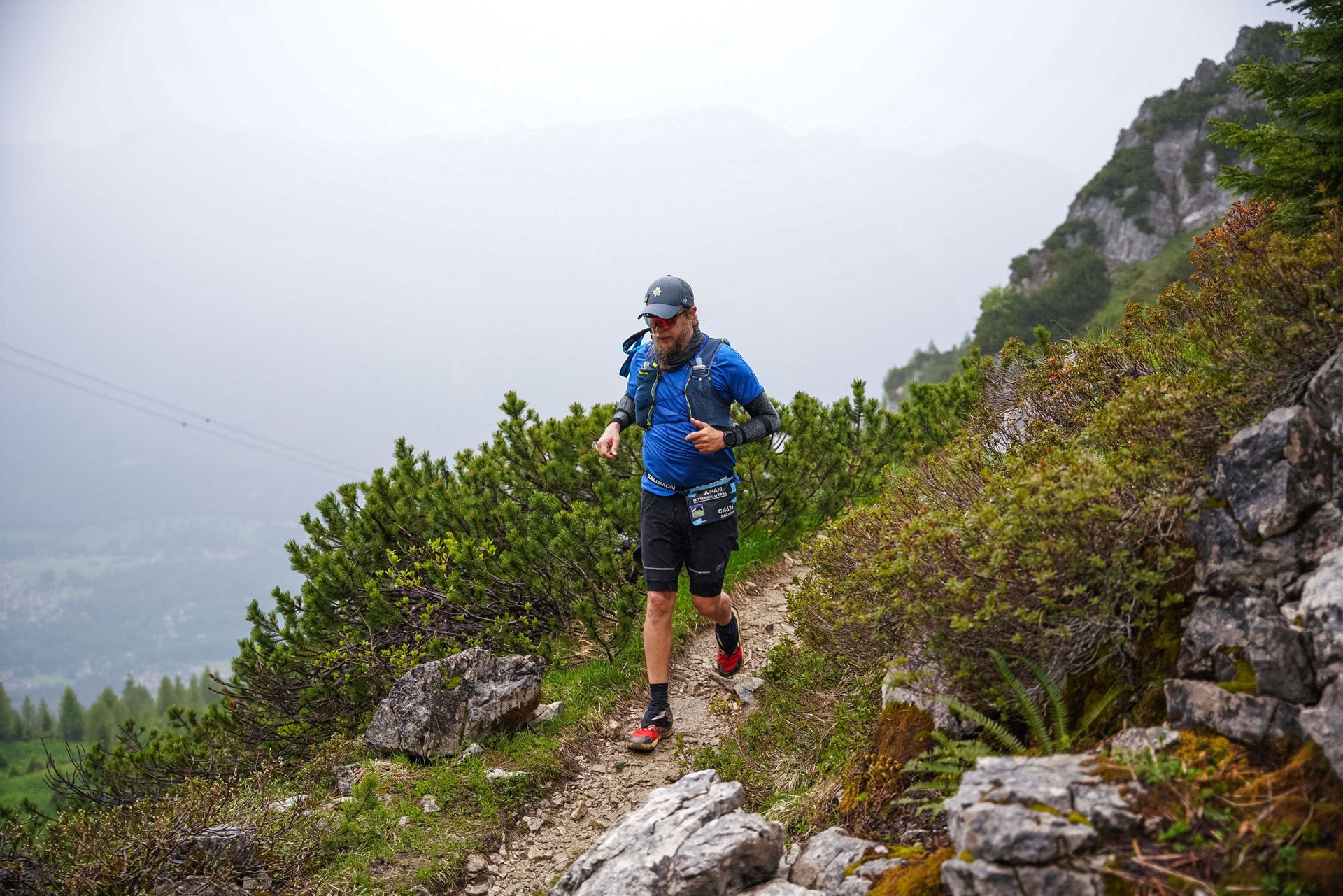 Juhani descending a high singletrack above the valley in the mist