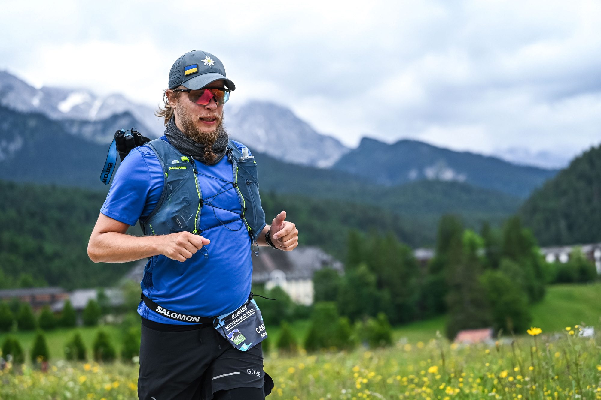 Juhani running on a trail with alpine peaks behind